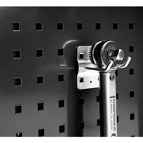 Detailaufnahme eines Drehmomentschlüssels an einer Lochwand. Die schwarze Wand hat quadratische Aussparungen. Das Werkzeug hat einen Metallkopf.